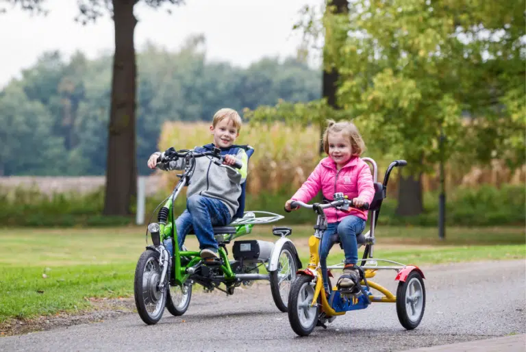 Zwei Kinder fahren auf Van Raam Dreirädern für Kinder