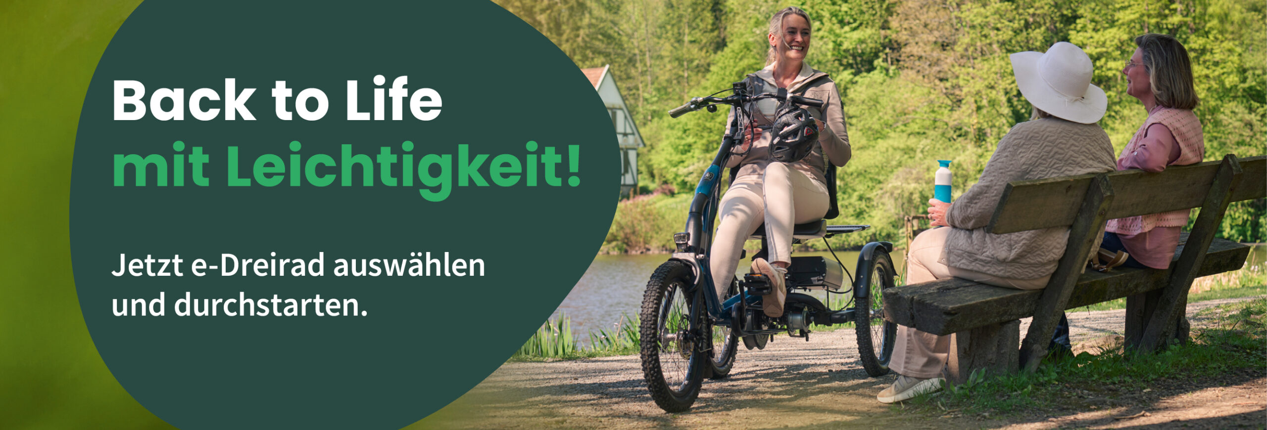 Eine Frau sitzt auf ihrem Dreirad vor ihr auf der Bank zwei weitere Frauen. Im Hintergrund der Schriftzug "Back to Life mit Leichtigkeit"